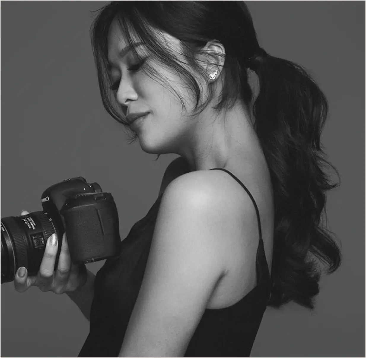 Black and white portrait of Stephanie Teo holding her camera